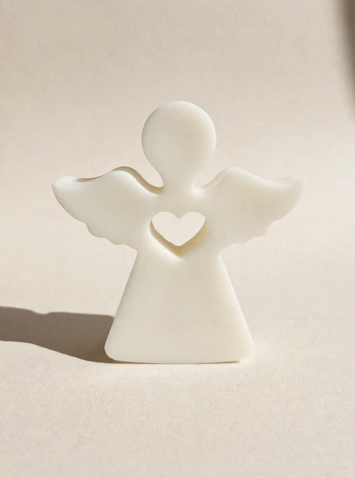 Figura de ángel con alas extendidas y corazón central en tono claro