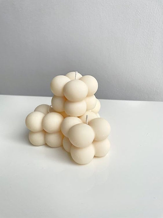 Velas mini burbuja color crema con formas redondeadas sobre una superficie blanca.